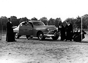 Six Christian Brothers investigate the distance of a Pontiac car from a pole